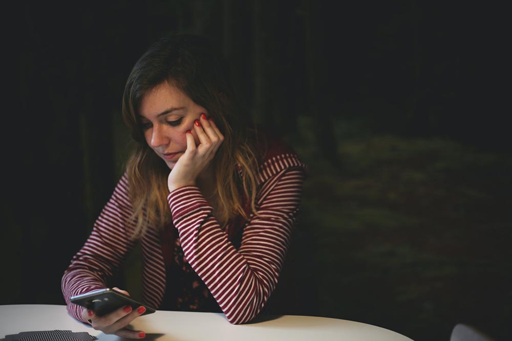 female looking at phone looking pensive.