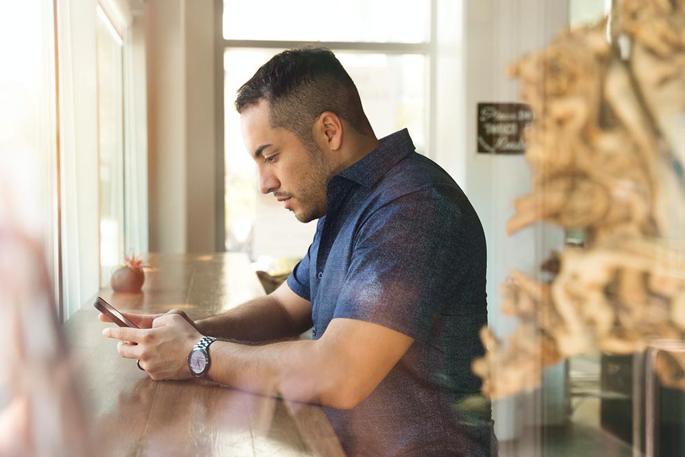 man browsing the internet using a smartphone in a coffee shop